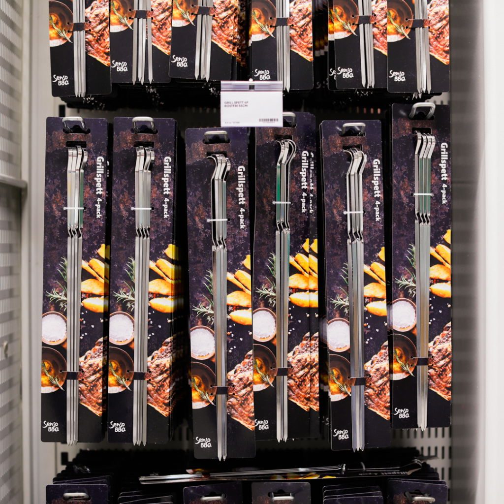 Grillspett i 4-pack för BBQ, förpackade med bilder av grillad mat och tillbehör, placerade på hylla i butik.