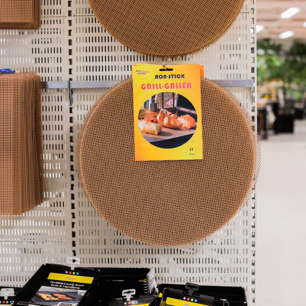Rund non-stick grillgaller hängande på en butikshylla, med en produktbeskrivning som visar användning för grillning av mat.