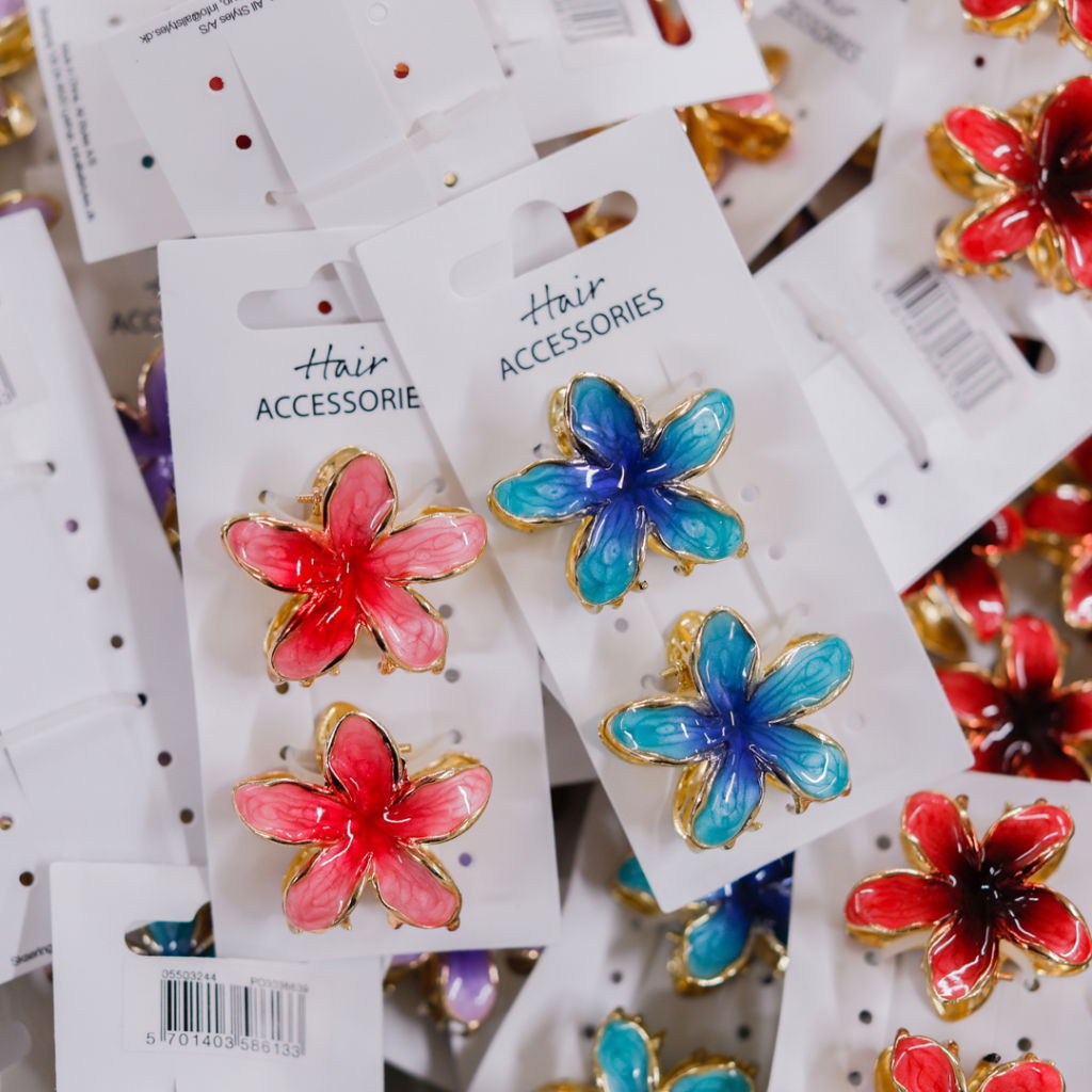 Färgglada håraccessoarer i form av blommor i rött och blått, förpackade på kort med etikett "Hair Accessories". Perfekta för att ge stil och färg till frisyrer.