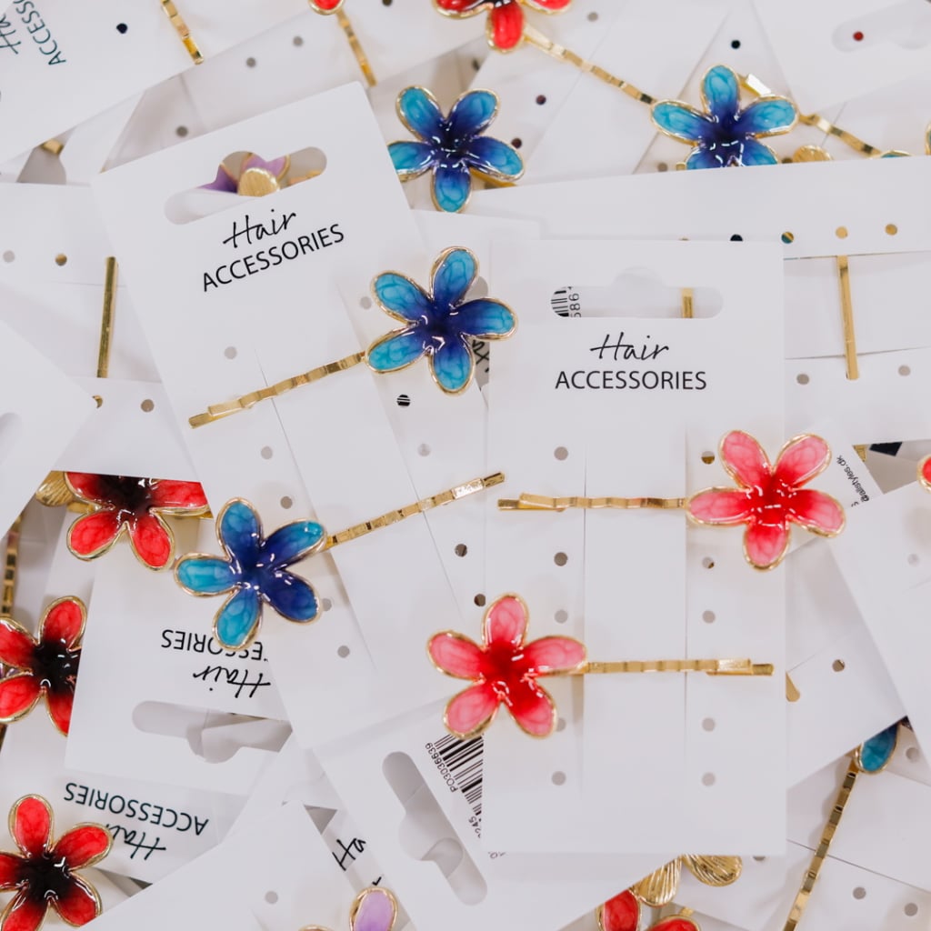 Flera färgglada håraccessoarer i form av blommor på vit bakgrund, med etiketter som visar "Hair Accessories".