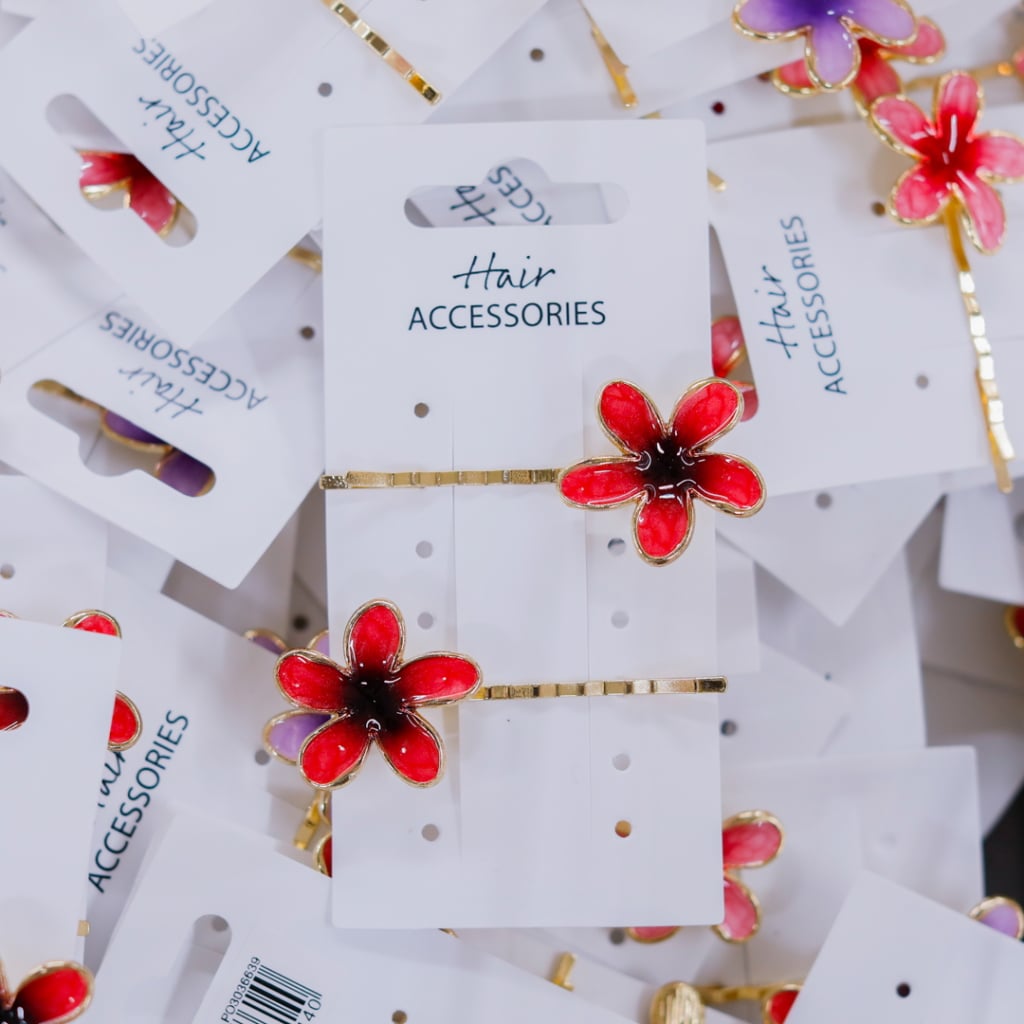 Flera håraccessoarer med blommotiv i röd och lila färg, presenterade på vita kort med texten "Hair Accessories".