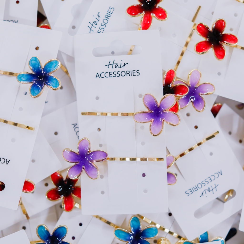 Färgglada håraccessoarer med blommotiv i blått, lila och rött, placerade på vita kort med texten "Hair Accessories". Perfekta för att piffa upp frisyrer.