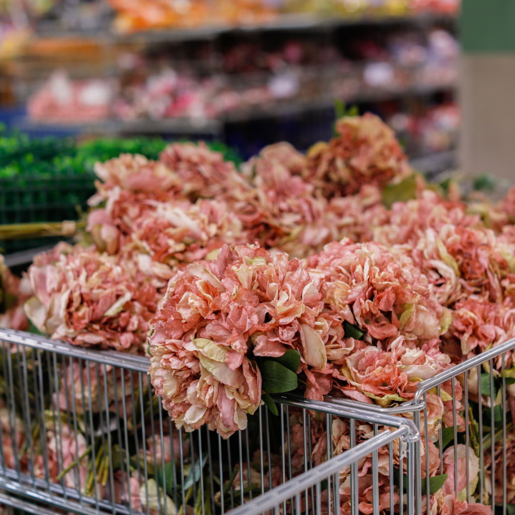 En korg fylld med rosa blommor i en blomsterbutik, med oskarpa bakgrunder som visar fler blommor och växter. Perfekt för dekorationer och arrangemang.