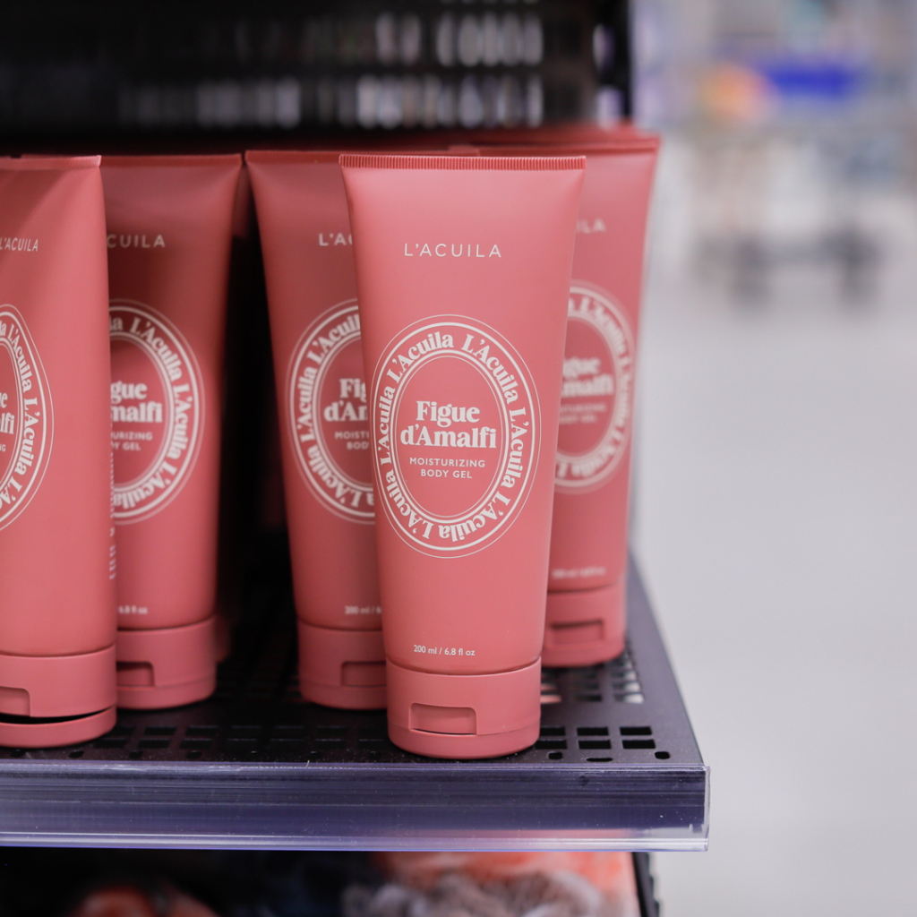 Fuktgivande kroppsgel Figue d'Amalfi från L'Acuia, förpackad i en rosa tub, placerad på en hylla i en butik. Produkten är 200 ml och erbjuder intensiv återfuktning för huden.