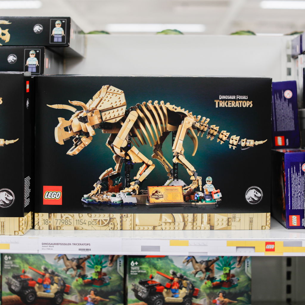 LEGO Triceratops dinosauriefossil set med 1154 bitar, förpackad i en färgglad låda, placerad på en hylla i en leksaksbutik.