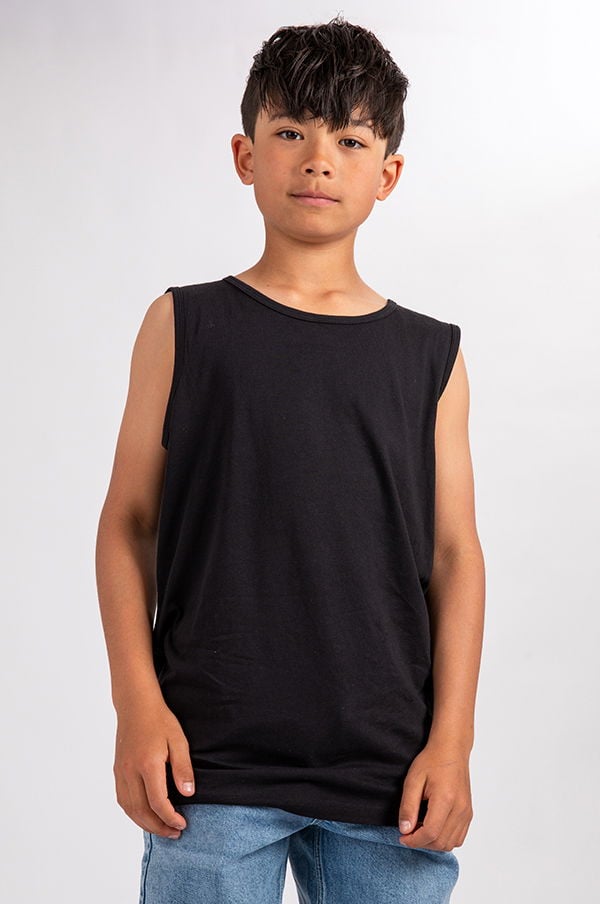 En pojke i svart ärmlös t-shirt poserar framför en vit bakgrund. Han har kort, mörkt hår och bär ljusa jeans. Bilden visar en avslappnad och modern stil för barnkläder.