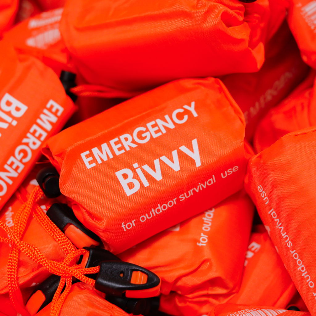 Nödbivvy i orange färg, designad för utomhusöverlevnad. Produkten är kompakt och lätt att transportera, vilket gör den idealisk för äventyr och nödsituationer.