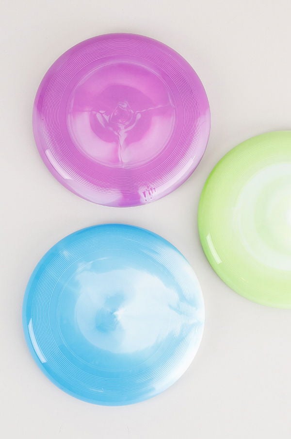 Flera färgglada frisbees i lila, blå och grön nyans, placerade på en ljus bakgrund. Perfekta för utomhusaktiviteter och spel.