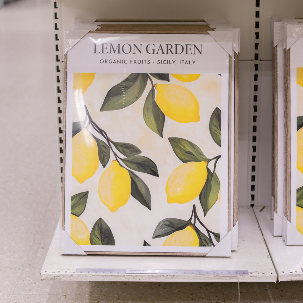Affisch med motiv av citroner och gröna blad, märkt "Lemon Garden - Ekologiska frukter - Sicilien, Italien", placerad på en hylla i en butik.