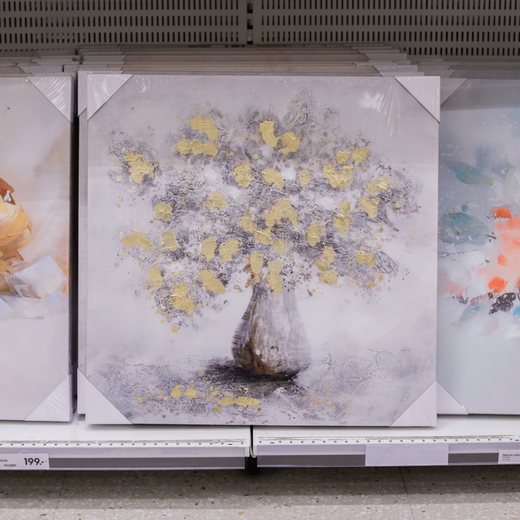Konstverk med en vas fylld med blommor i guld och grå nyanser, inramad och tillgänglig för försäljning i en butik.