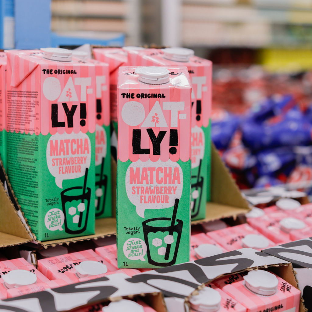 Oatly matcha-jordgubb dryck i kartong på hylla, helt växtbaserad och veganvänlig, 1 liter förpackningar synliga i butiksmiljö.