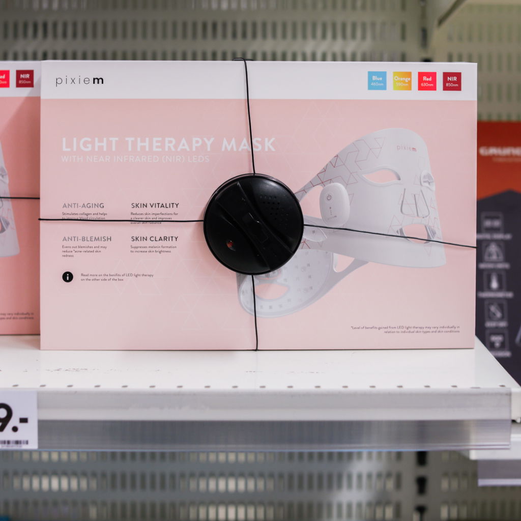 Ljusbehandlingmask med nära infraröda LED-lampor från Pixiem, designad för att motverka ålderstecken, förbättra hudens klarhet och vitalitet. Produkten är förpackad med information om dess fördelar, inklusive anti-blemmor och anti-aging egenskaper.