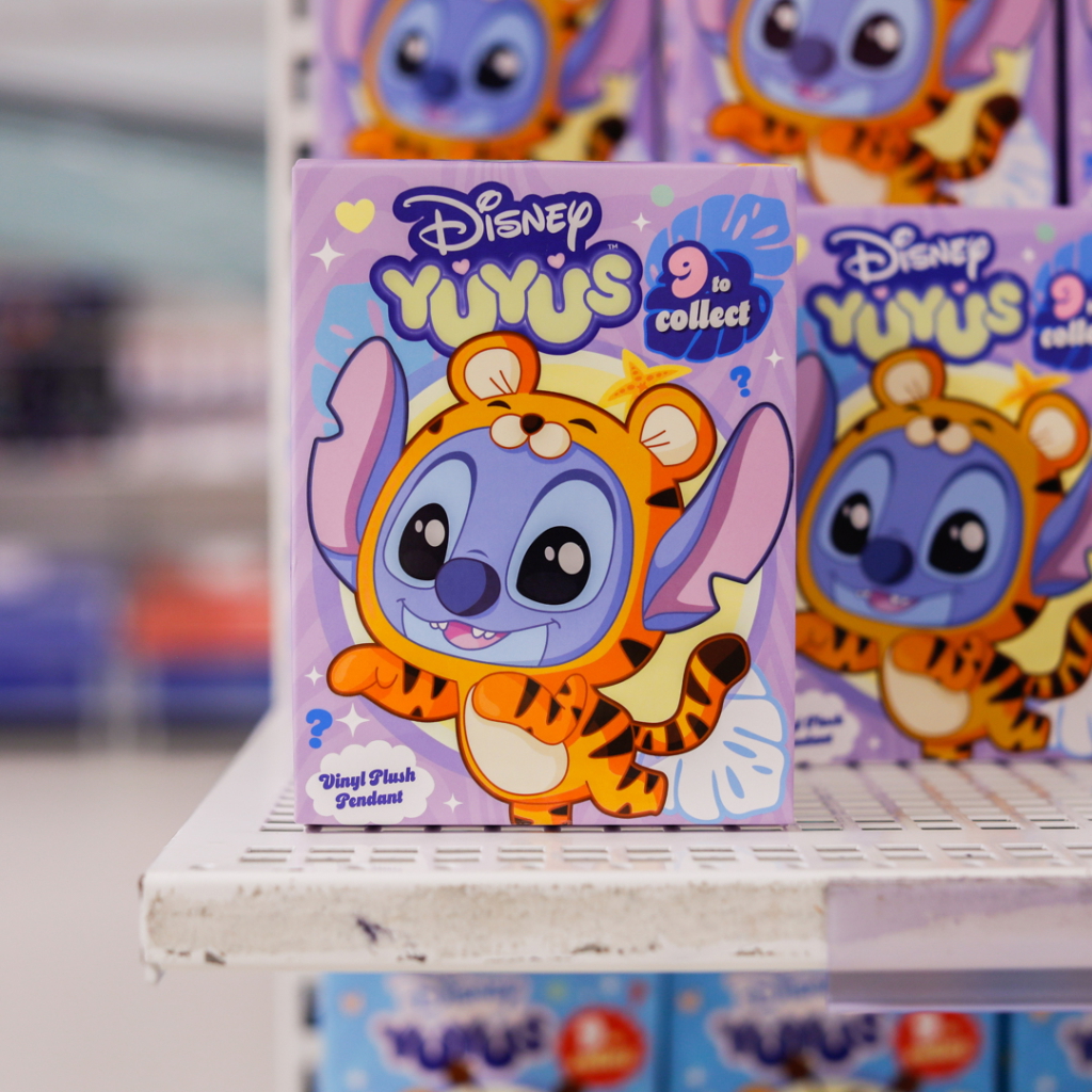 Disney Yiyus vinylplushpendant i tigerdesign. Boxen visar en glad karaktär med stora öron och ett färgglatt mönster. Samla alla nio figurer.